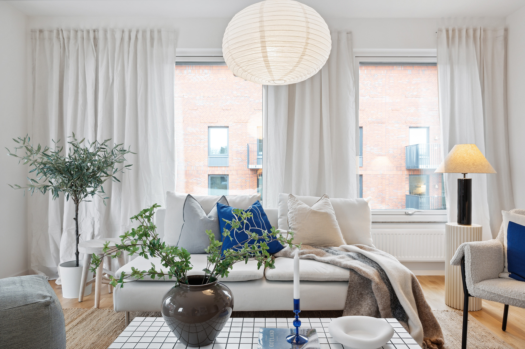 Vardagsrum med härliga fönster, soffa, bord och lampa i Serneke Bostad-lägenhet