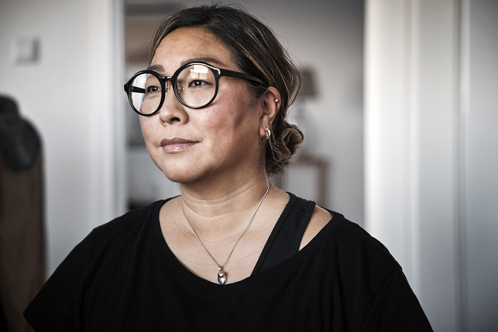 Person med glasögon tittar ut från nyproducerad lägenhet av Serneke Bostad.