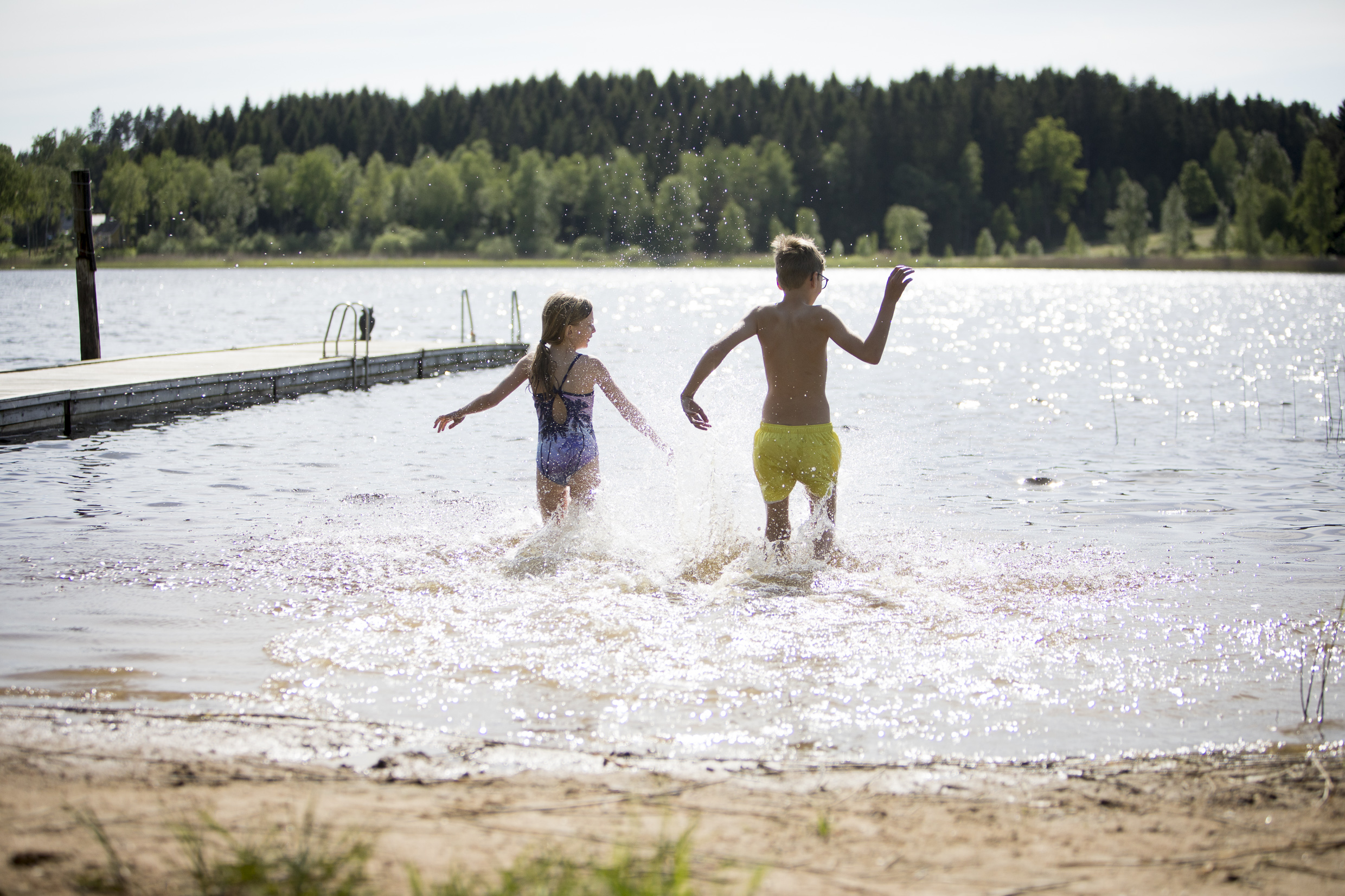 Två barn som badar och springer från stranden