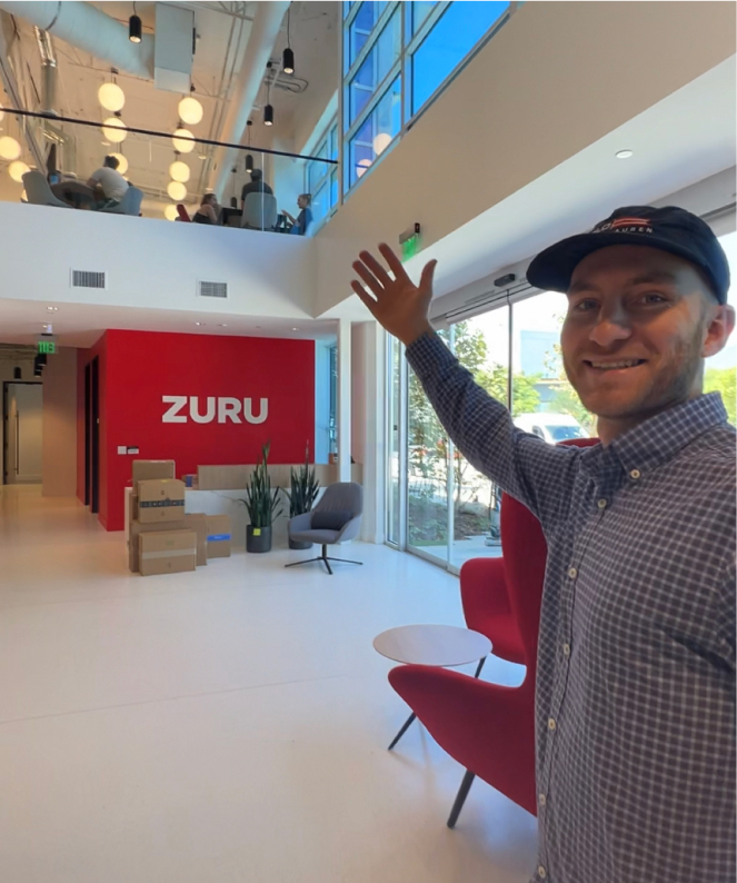 Personne faisant visiter le bureau de ZURU, logo rouge de ZURU sur le mur en arrière-plan.