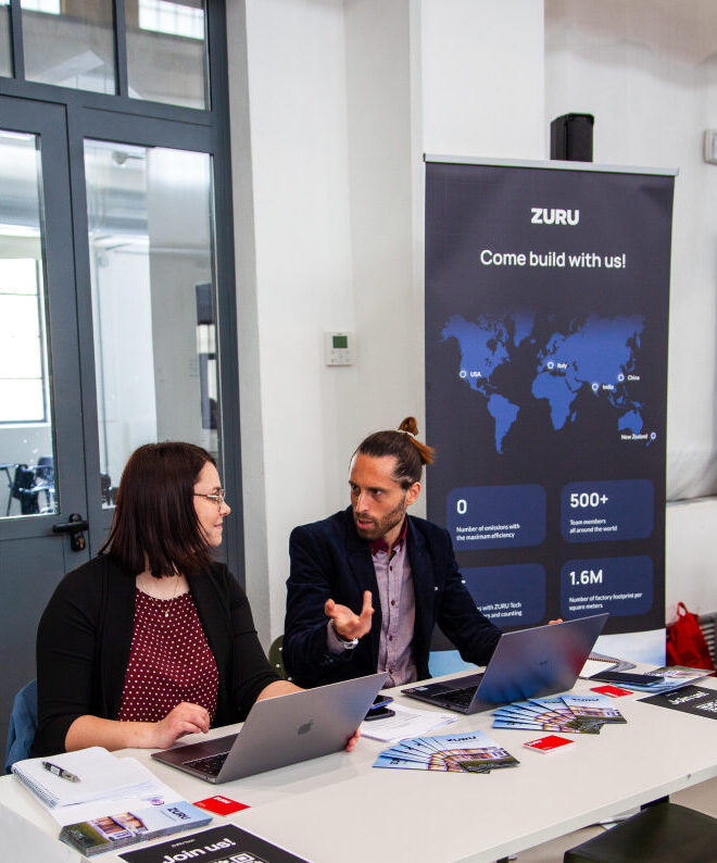 Deux recruteurs faisant la promotion de ZURU assis à un bureau lors d'un salon.