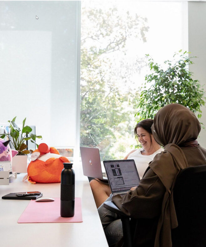 Deux collègues de travail assis à un bureau avec des ordinateurs portables